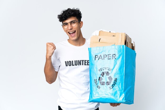 Jeune homme tenant un sac de recyclage plein de papier célébrant une victoire