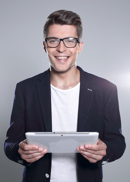 Jeune homme tenant une tablette dans ses mains regardant quelque chose et souriant