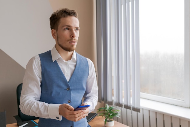 Jeune homme tenant un téléphone portable communiquant et recevant la lecture de messages texte