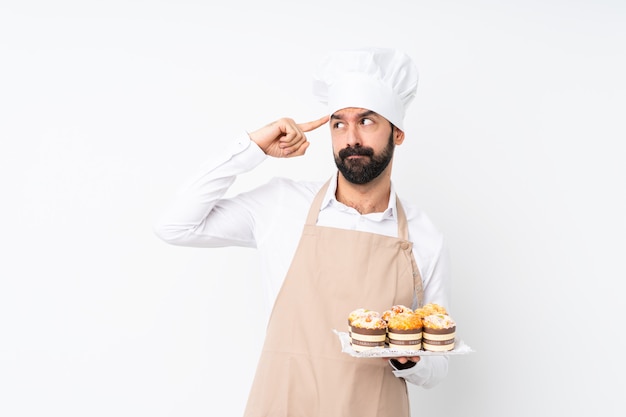 Jeune homme, tenue, gâteau muffin, sur, blanc, mur, avoir, doutes, et, penser