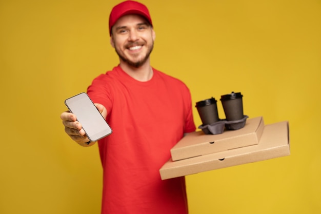 Jeune homme, tenue, pizza, et, smartphone, isolé, sur, mur jaune