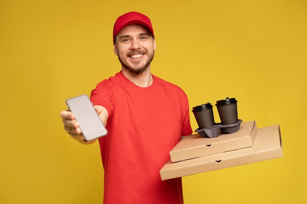 Jeune homme, tenue, pizza, et, smartphone, isolé, sur, mur jaune