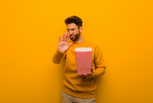 Jeune homme, tenue, pop-corns, mettre, main devant