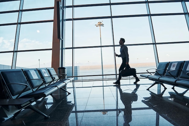 Jeune homme en tenue de soirée est à l'aéroport moderne Conception de vacances