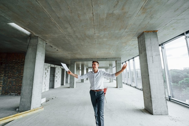 Un jeune homme en tenue de soirée qui réussit travaille à l'intérieur sur la construction