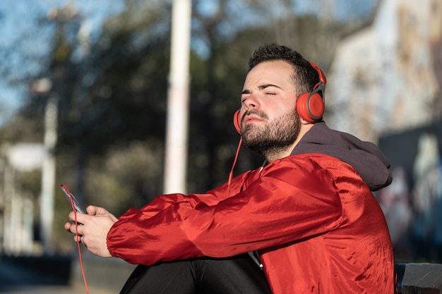 Jeune homme en tenue de sport, écouter de la musique avec une paire d'écouteurs