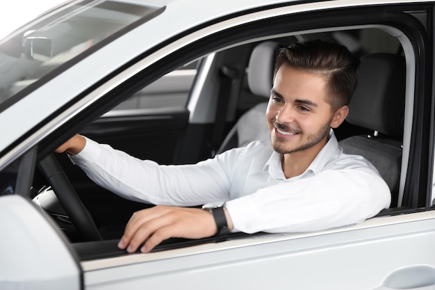 Jeune homme testant une nouvelle voiture dans un salon