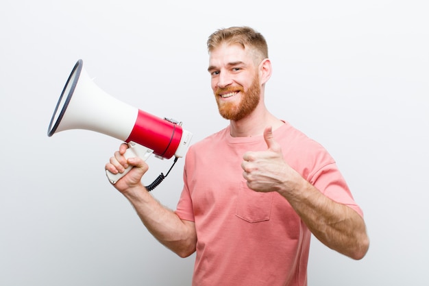 Jeune homme tête rouge avec un mégaphone contre blanc