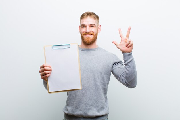 Jeune homme tête rouge montrant un document sur fond blanc