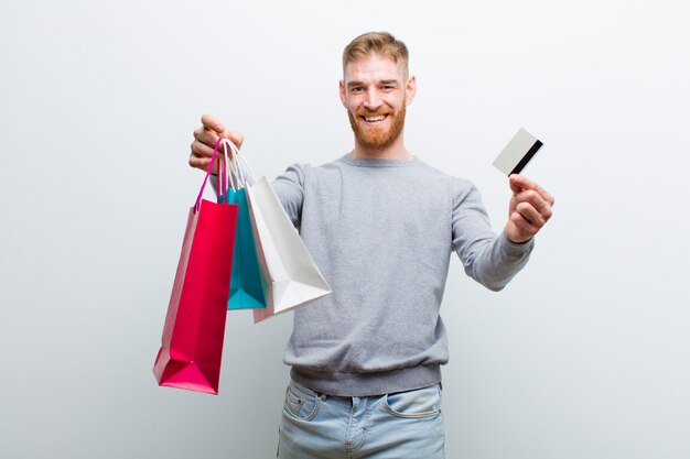 Jeune homme à la tête rouge avec des sacs à provisions blanc