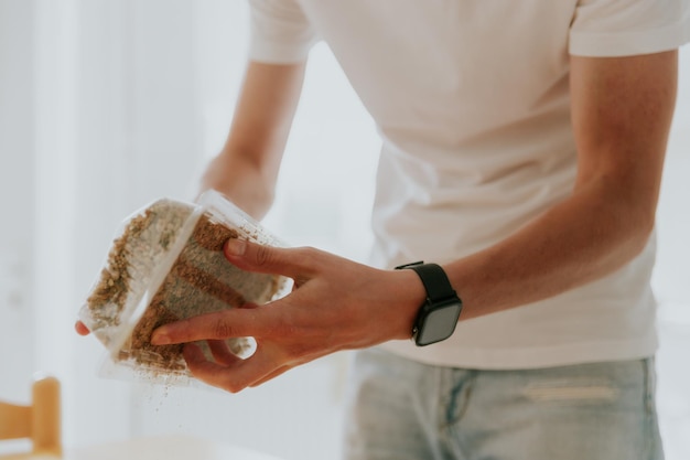 Un jeune homme tient une boîte avec du remplissage pour planter du blé