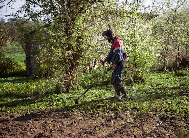 Jeune homme tond l'herbe avec une tondeuse