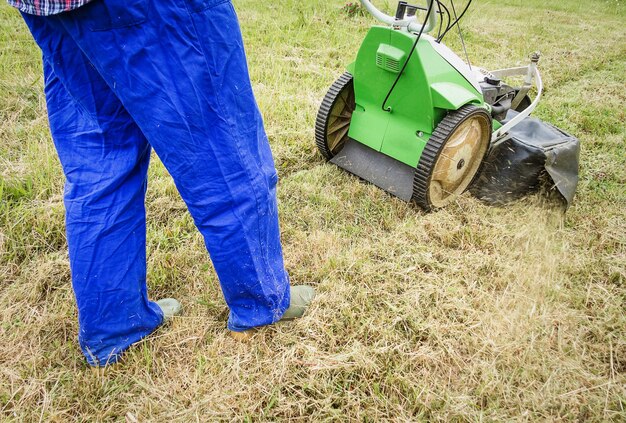 Jeune homme tondant la pelouse avec une tondeuse à gazon