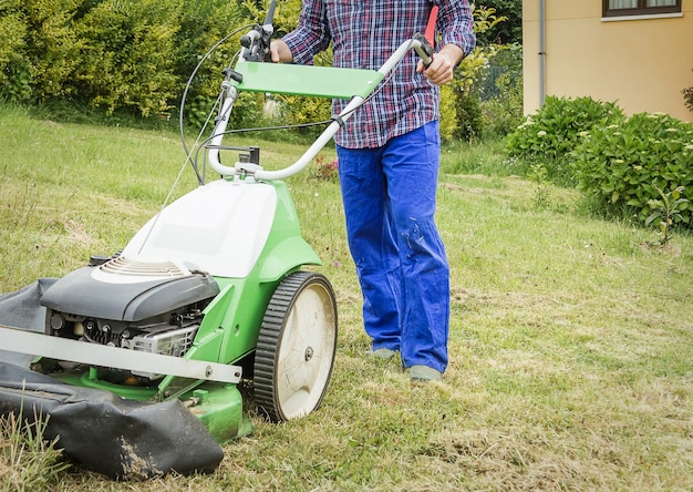 Jeune homme tondant la pelouse avec une tondeuse à gazon