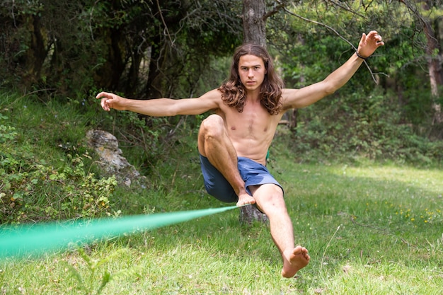 Jeune homme, à, torse nu, équilibrer, sur, slackline, dans, champ vert, sur, été