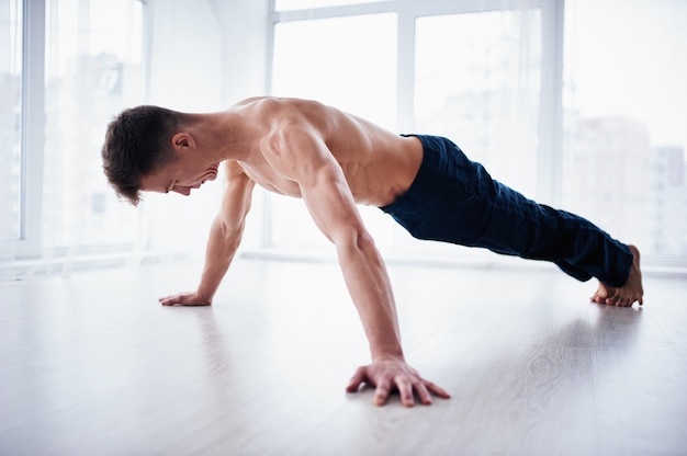 Jeune homme torse nu fort pratique le yoga au studio de yoga