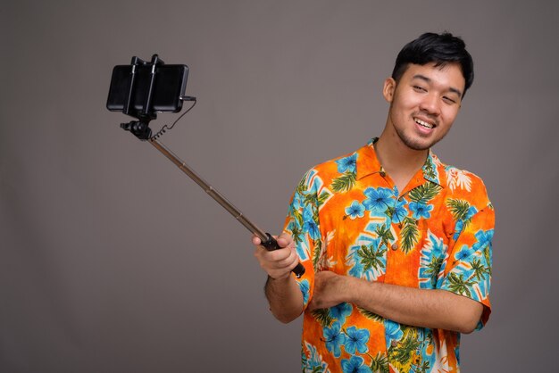 Jeune homme touriste asiatique prêt pour les vacances contre le gris