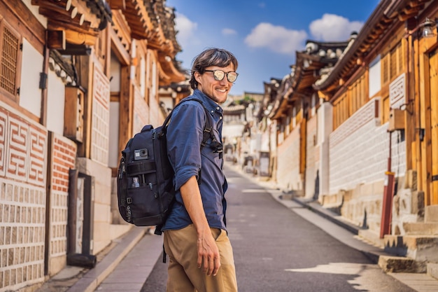 Photo jeune homme touriste dans le village de bukchon hanok est l'un des endroits célèbres pour les maisons traditionnelles coréennes ont été préservées voyage en corée concept