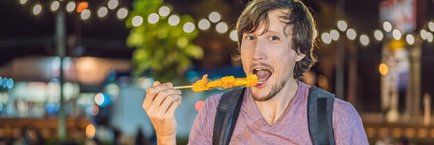 Jeune homme touriste sur la rue piétonne du marché alimentaire asiatique bannière format long