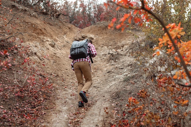 Jeune homme touristique avec sac à dos en remontant le sentier sur la nature. guy randonnée, vue arrière.