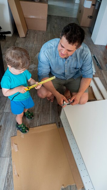 Jeune homme avec un tournevis et un enfant installant un meuble