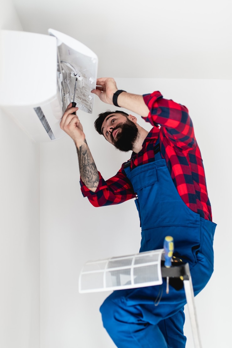 Photo jeune homme à tout faire barbu réparant le climatiseur.