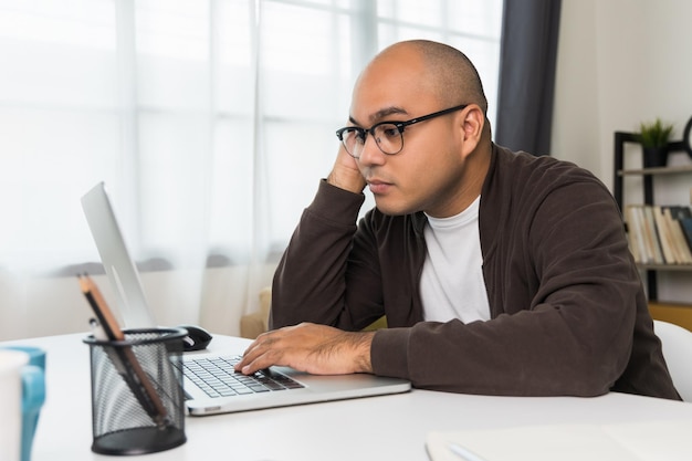 Le jeune homme travaillait devant l'ordinateur portable, il était fatigué et s'est endormi sur le bureau