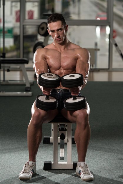 Jeune homme travaillant sur les boucles de concentration d'haltères biceps