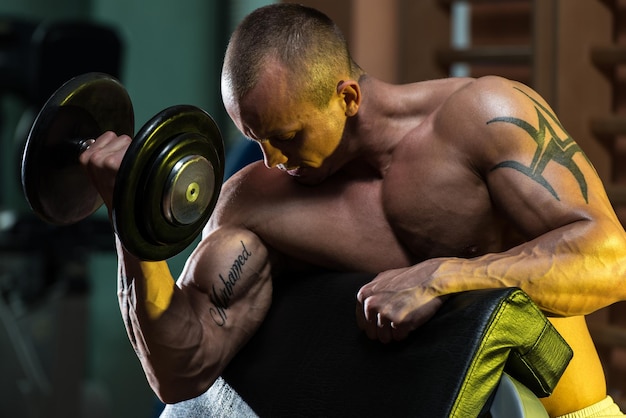 Jeune homme travaillant sur les boucles de concentration d'haltères biceps