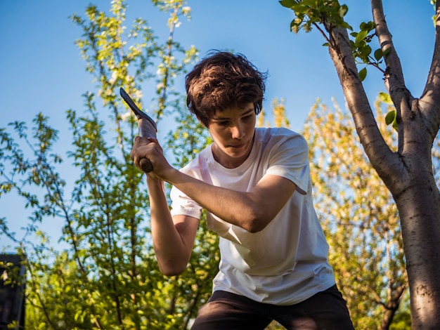 Jeune homme travaillant dans le jardin avec une hache près de l&#39;arbre