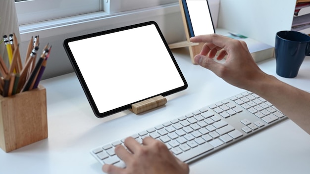 Jeune homme travaillant en ligne avec une tablette numérique sur un tableau blanc au bureau à domicile.