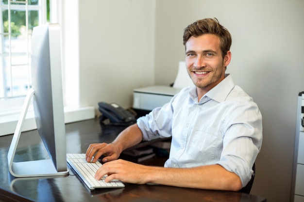 Jeune homme travaillant sur l'ordinateur de bureau