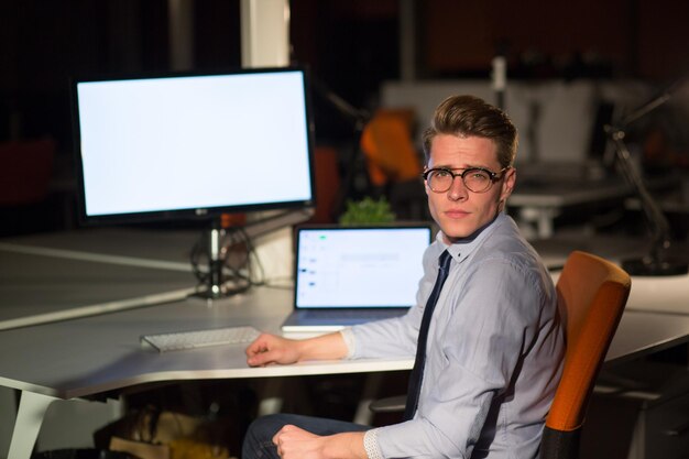 Photo jeune homme travaillant sur ordinateur la nuit dans un bureau sombre. le dessinateur travaille plus tard.