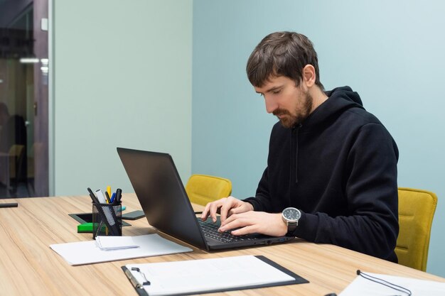 Jeune homme travaillant sur un ordinateur portable assis sur son lieu de travail au bureau