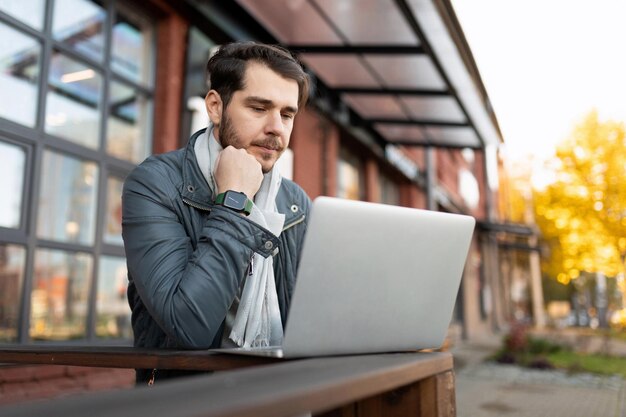 Jeune homme travaillant sur un ordinateur portable à l'extérieur