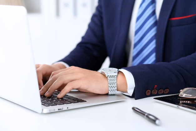 Jeune homme travaillant avec un ordinateur portable, les mains de l'homme sur un ordinateur portable, un homme d'affaires sur le lieu de travail.