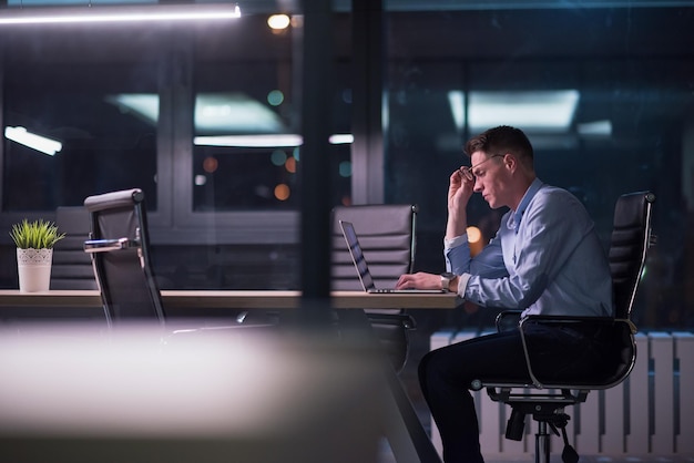 Jeune homme travaillant sur ordinateur portable la nuit dans un bureau sombre. Le dessinateur travaille plus tard.