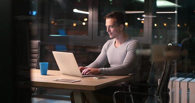 Jeune homme travaillant sur ordinateur portable la nuit dans un bureau sombre. Le dessinateur travaille plus tard.