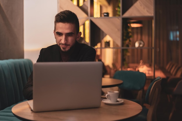 Jeune homme travaillant sur un ordinateur portable à son bureau pendant la nuit