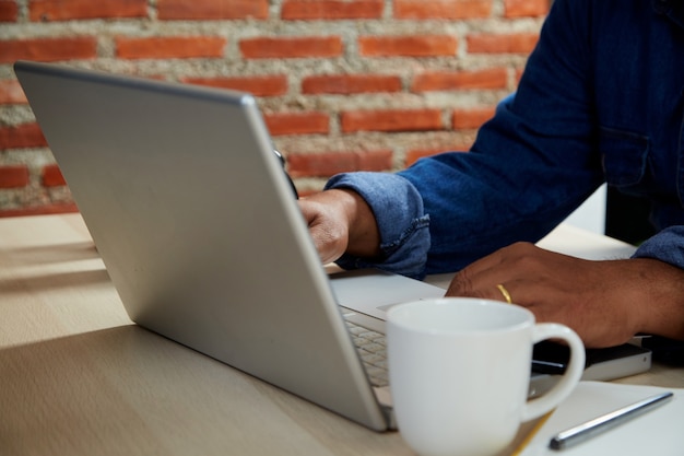 Jeune homme travaillant sur ordinateur à table à l'intérieur