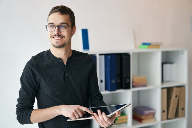 Jeune homme travaillant avec une tablette recevant un appel vidéo parlant avec des partenaires