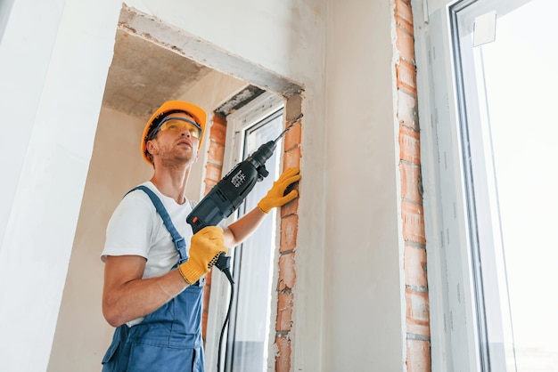 Jeune homme travaillant en uniforme à la construction pendant la journée