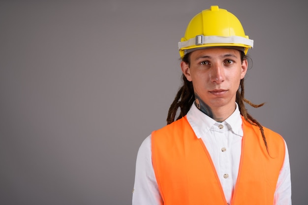 Jeune homme travailleur de la construction sur fond gris