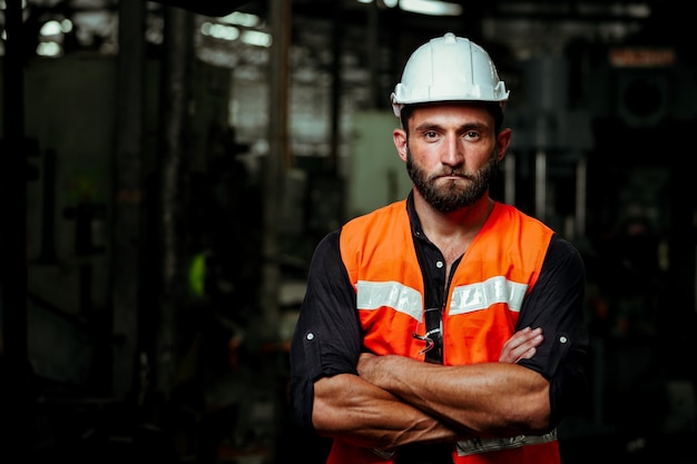 Photo jeune homme travailleur industriel travaillant avec une machine en métal en usine avec de nombreux équipements