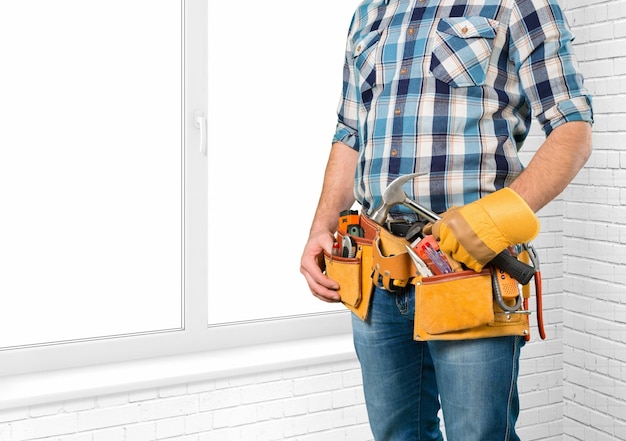 Jeune homme travailleur en uniforme avec ceinture jaune et outils