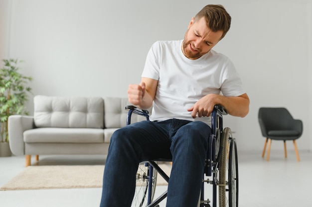 Jeune homme triste dans un fauteuil roulant à la maison