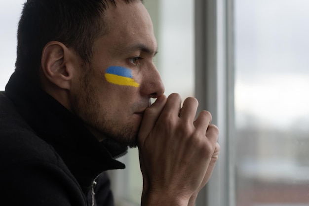 Jeune homme triste avec le symbole du drapeau ukrainien sur son visage pleurant arrêter le concept de guerre priez pour l'Ukraine