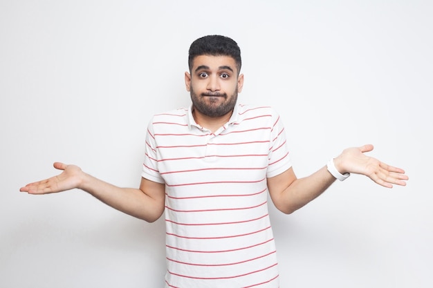 Jeune homme en tshirt rayé debout avec les bras levés et ne sait pas quoi faire