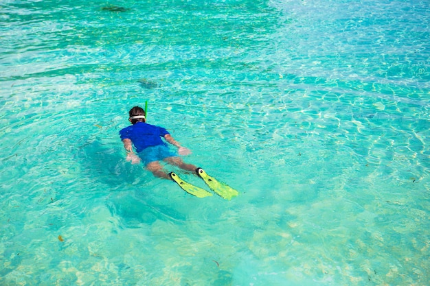 Jeune homme avec tuba dans les eaux turquoises claires