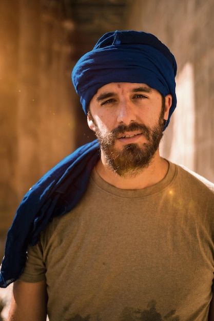 Photo jeune homme en turban bleu marchant sur les colonnes du temple d'edfou